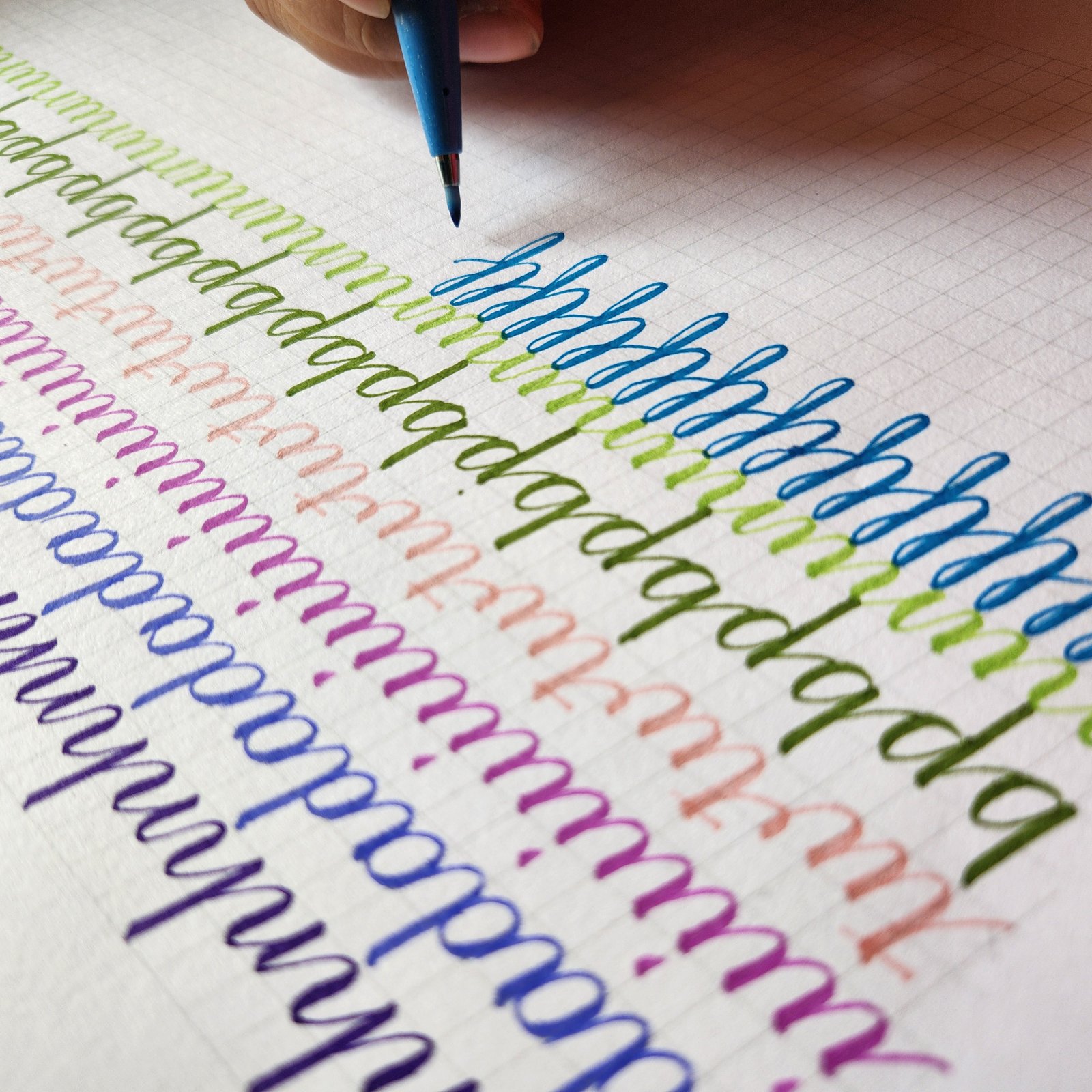 Brush pen letter drills in green, blue, pink and violet on guideline paper