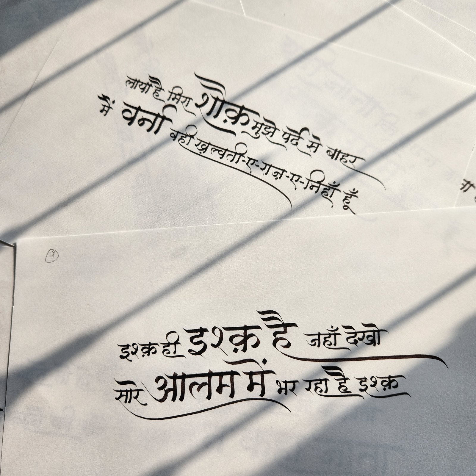 Two Devanagari couplets on paper, lit by window shadows