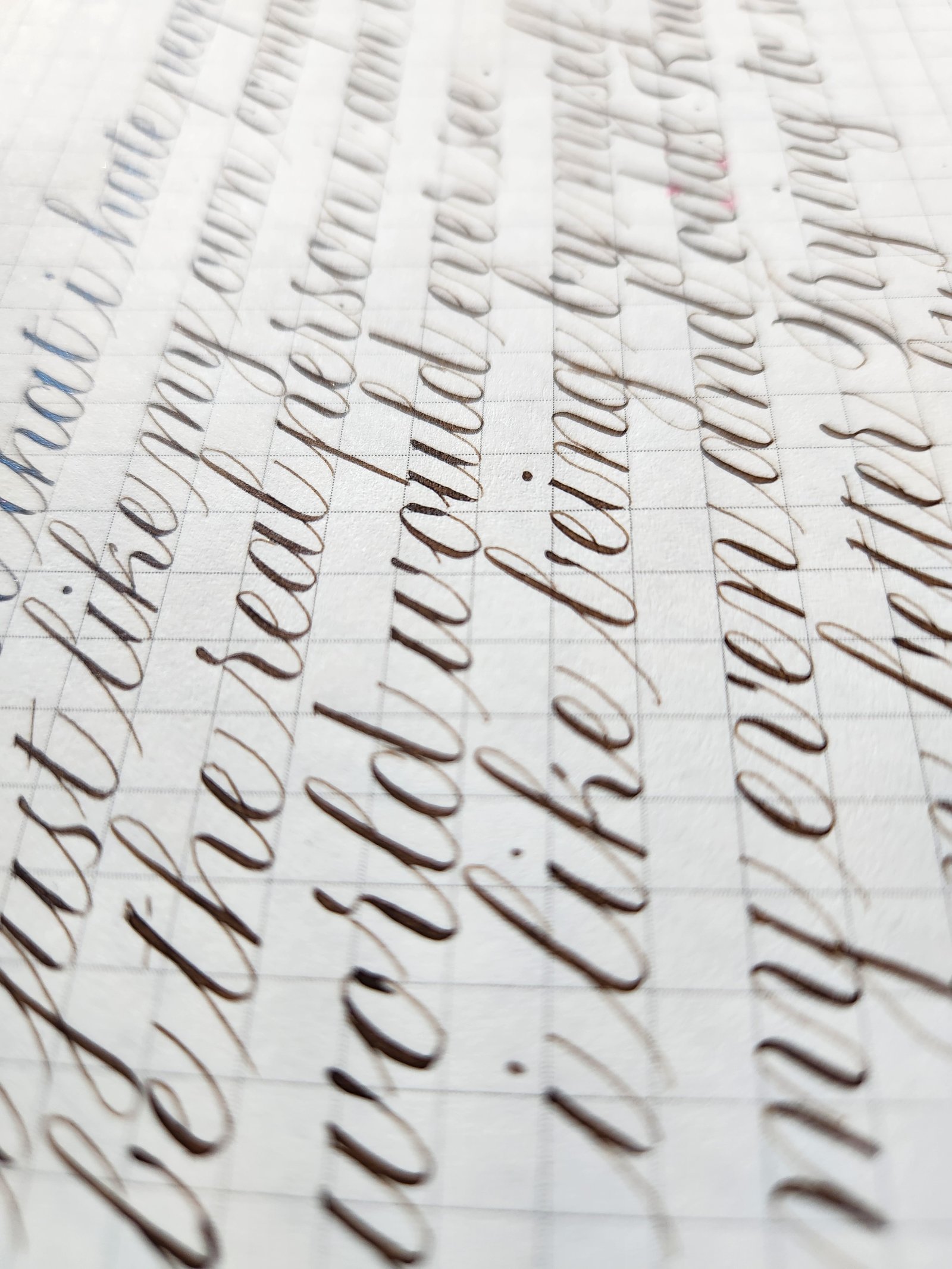 Copperplate practice in brown ink on ruled guideline paper