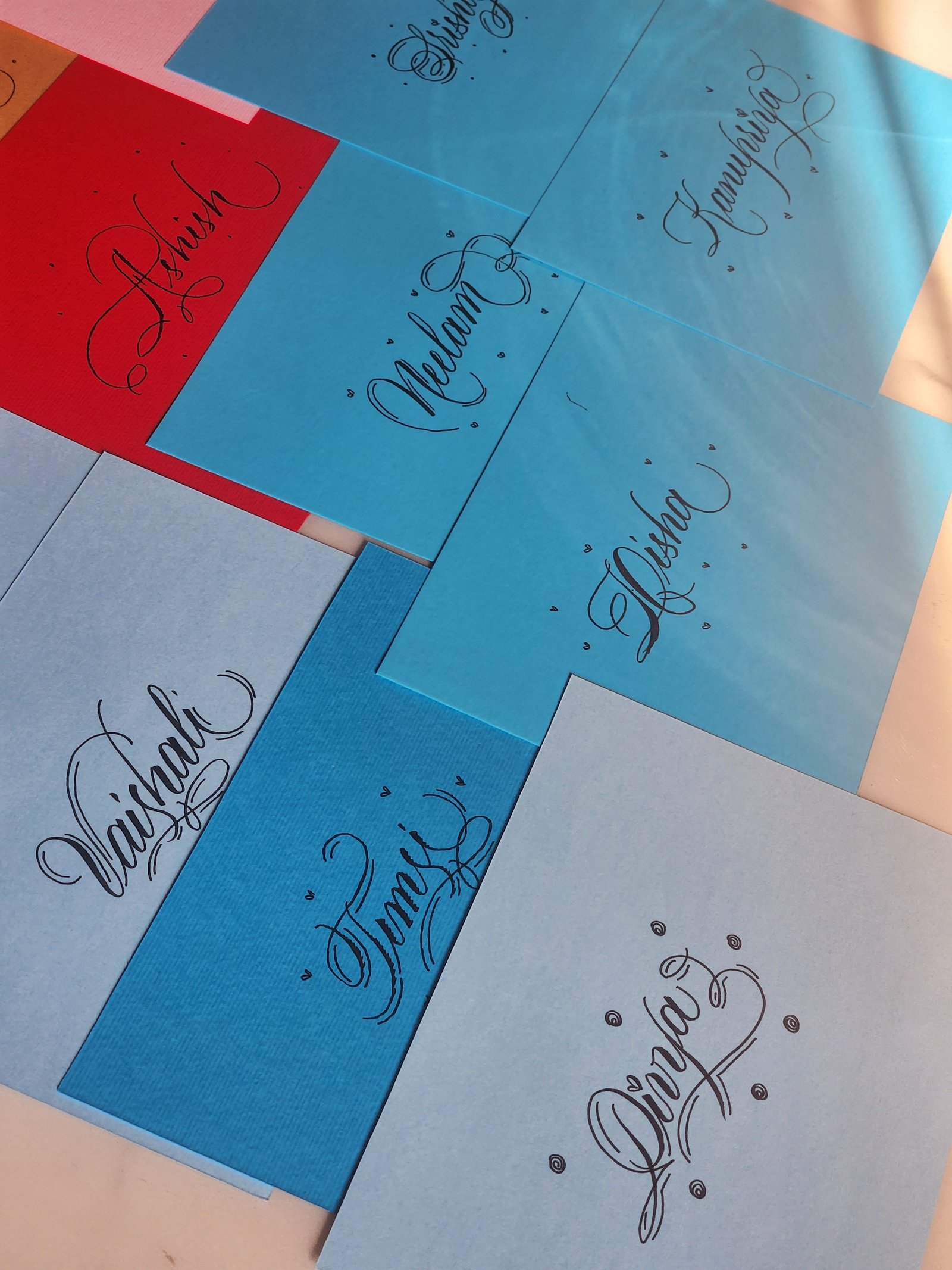 Flourished name cards lettered in black on red and blue paper